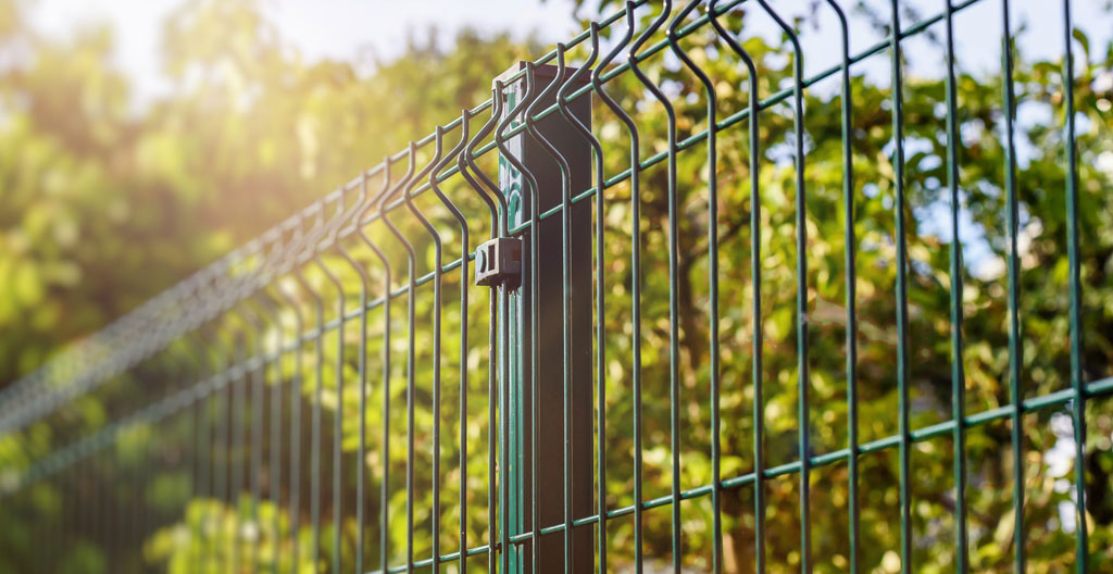 Vue d'ensemble d'un jardin résidentiel français contemporain avec clôture rigide anthracite installée en arrière-plan, pelouse entretenue et terrasse moderne